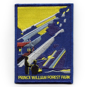 Może przedstawiać: Naszywka haftowana na niebiesko z żółtym i białym wzorem. Naszywka zawiera napis "Prince William Forest Park" żółtymi literami.