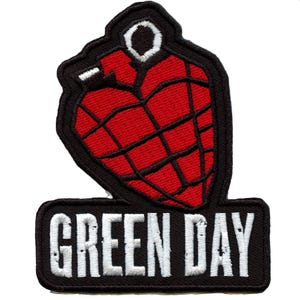 Puede incluir: Parche bordado en negro y rojo con una granada estilizada en forma de corazón y el texto "GREEN DAY" en blanco.
