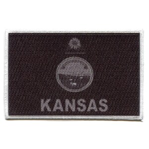 May include: A black and white embroidered patch with the word "KANSAS" and a stylized sunflower design.