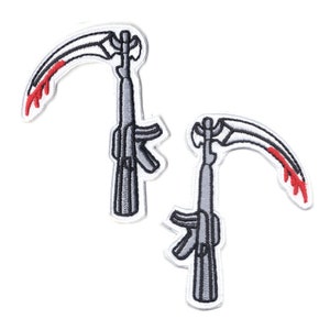 Könnte beinhalten: Zwei gestickte Patches, die ein stilisiertes Gewehr mit einer gebogenen Klinge darstellen, die einer Sense ähnelt, mit roten Akzenten.