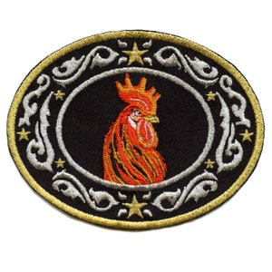 Pode incluir: Etiqueta bordada com um galo vermelho com uma coroa dourada sobre fundo preto. O galo é rodeado por uma borda decorativa prateada e dourada com estrelas.