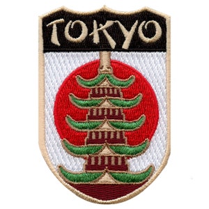 May include: Embroidered patch with a white background and a tan border. The patch features a red circle with a stylized pagoda in the center. The text "TOKYO" is embroidered in black on a tan banner above the circle.