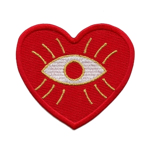May include: Red felt heart-shaped patch with a white eye and gold rays emanating from it.