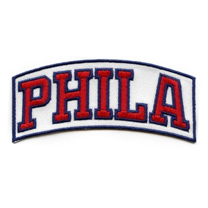May include: White fabric patch with blue edging and the word "PHILA" embroidered in red.