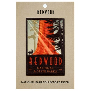 May include: Embroidered patch featuring a vintage-style illustration of a giant redwood tree, a deer, and sunbeams. The patch is black with white text and a red border. It reads 'Redwood National & State Parks'.