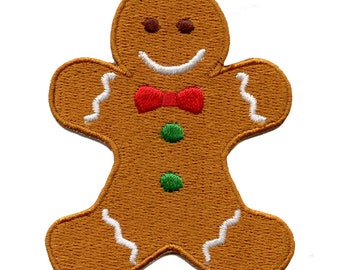Op de afbeelding: Een geborduurde gingerbread man patch met een rode strik en groene knopen. De patch is bruin met witte glazuurdetails.
