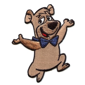 May include: Embroidered patch of a brown cartoon bear wearing a blue bow tie. The bear is smiling and has its arms outstretched.