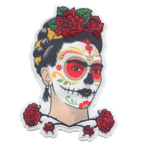 May include: Embroidered iron-on patch featuring a colorful Day of the Dead inspired portrait of Frida Kahlo with red roses.