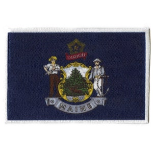 May include: A blue patch with a white border featuring the state seal of Maine. The seal depicts a pine tree, a farmer, and a sailor with the words "DIRIGO" and "MAINE" around the pine tree.