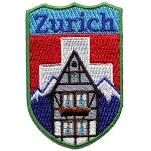 Puede incluir: Parche bordado con el nombre de la ciudad "Zurich" en letras azules sobre un fondo azul y blanco. El parche presenta una cruz roja con un centro blanco y una casa gris con ventanas blancas y una jardinera roja. La casa está situada en un paisaje de montaña azul y blanco. El parche está rodeado por un borde verde.