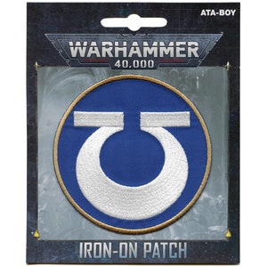 May include: Warhammer 40,000 Iron-On Patch featuring a white symbol on a blue circle with a gold border.