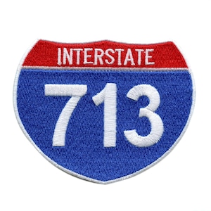 May include: A blue and red interstate highway sign with the number 713 in white.