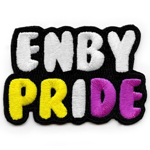 Op de afbeelding: Gestikt patch met de tekst "ENBY PRIDE" in witte, gele en paarse letters op een zwarte achtergrond.