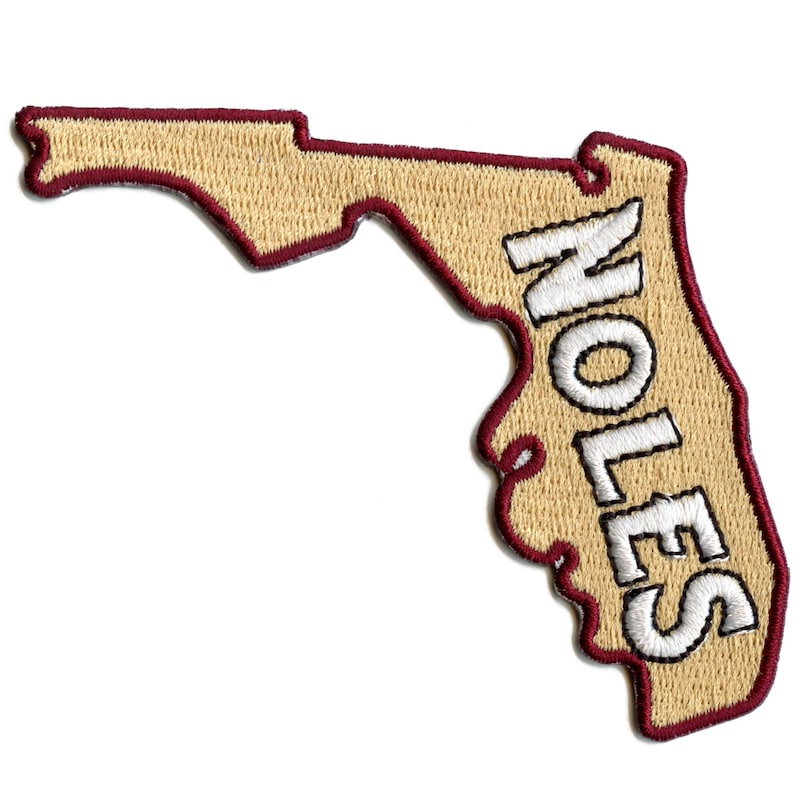 May include: Embroidered patch in the shape of Florida, with the word "NOLES" in white block letters. The patch has a tan background with a maroon border and text.