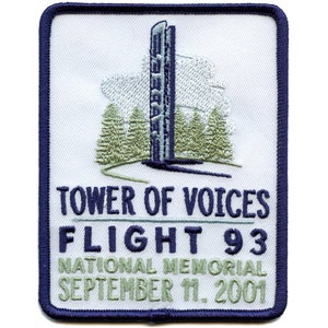 Puede incluir: Un parche bordado blanco con un borde azul. El parche presenta una torre gris con una nube blanca sobre ella. El texto "Tower of Voices Flight 93 National Memorial September 11, 2001" está bordado en azul.