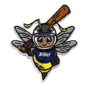 Puede incluir: Un parche bordado con una abeja de dibujos animados que lleva un casco de béisbol y sostiene un bate. La abeja lleva un uniforme azul y amarillo con la palabra "Killer" en la parte delantera. La abeja tiene alas y un aguijón.