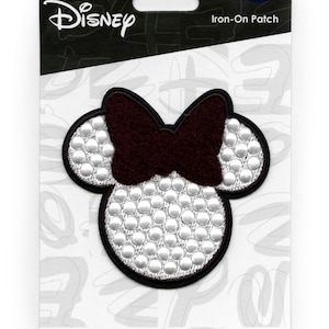 May include: Iron-on patch featuring a white and silver Minnie Mouse head with a burgundy bow. The patch has a black outline and is packaged on a white card with the Disney logo and the text "Iron-On Patch".