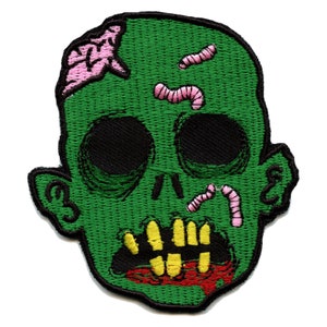 May include: Green zombie head with pink brains and pink worms embroidered on a green fabric patch.
