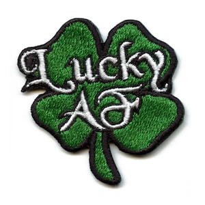 May include: Green four-leaf clover patch with white embroidered text that reads "Lucky AF".