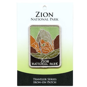 Puede incluir: Un parche para planchar con una imagen bordada de colores de una cordillera con el texto "Zion National Park" en letras blancas. El parche está empaquetado en una tarjeta blanca con el texto "Zion National Park" y "Traveler Series Iron-On Patch".