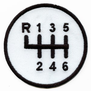 May include: White circular patch with a black embroidered gear shift pattern. The numbers 1, 3, 5, 2, 4, and 6 are displayed around the pattern. The letter R is displayed above the pattern.