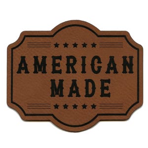 Könnte beinhalten: Braunes Leder-Etikett mit schwarzem Text, der "AMERICAN MADE" lautet, mit fünf Sternen über und unter dem Text.
