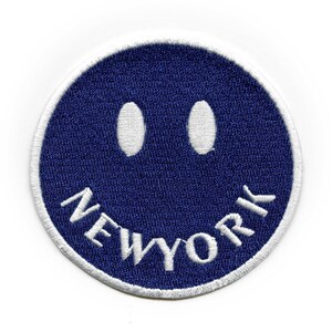 May include: A blue and white embroidered patch with a smiley face and the word "NEW YORK" underneath.
