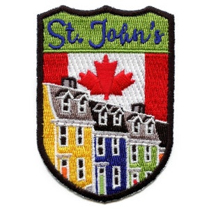 May include: Embroidered patch featuring a shield-shaped design with the text "St. John's" in blue cursive lettering on a green background. The shield also depicts a Canadian flag with a red maple leaf, and a row of colourful houses.