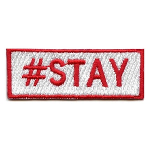 Puede incluir: Parche blanco bordado con borde rojo. El parche dice "#STAY" en rojo.