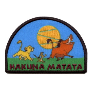 May include: An embroidered patch featuring Simba, Pumbaa, and Timon from Disney's The Lion King. The patch is a half-circle shape with a blue background and a yellow sun. The text "Hakuna Matata" is written in maroon at the bottom of the patch.
