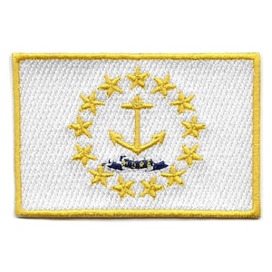 May include: A white embroidered patch with a gold border featuring the state flag of Rhode Island. The flag depicts a white anchor with a blue and white ship's wheel at the base, surrounded by thirteen gold stars.