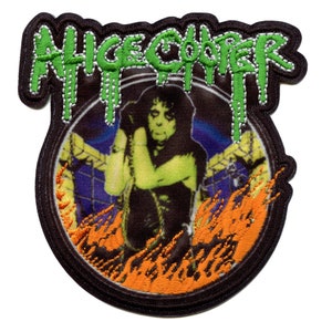 May include: A black and green embroidered patch with the text "ALICE COOPER" in green dripping letters. The patch features a black and white image of Alice Cooper in a black outfit with flames behind him.