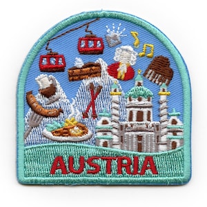 Op de afbeelding: Een blauwe en groene geborduurde patch met een afbeelding van Oostenrijkse bezienswaardigheden, waaronder een kerk, bergen en een skilift. De tekst "AUSTRIA" is onderaan de patch in rood geborduurd.