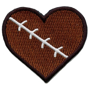 May include: A brown felt heart-shaped patch with a white stitched design resembling a stitched-up wound.
