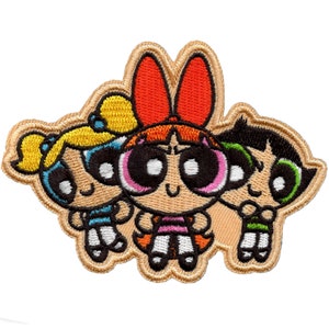 Può includere: Una toppa ricamata con le Powerpuff Girls,  Blossom, Bubbles e Buttercup. La toppa è beige con un contorno bianco e presenta le ragazze nelle loro pose caratteristiche.