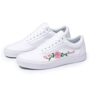 May include: White canvas low-top sneakers with pink and green embroidered flowers.