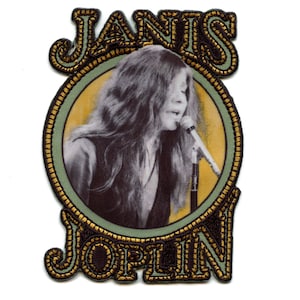 May include: A gold and black embroidered patch with a photo of Janis Joplin singing into a microphone. The patch has the text "JANIS JOPLIN" around the photo.