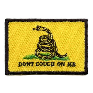 May include: A yellow patch with a black snake coiled around a green stem. The snake has a black head with a forked tongue. The text "DONT COUGH ON ME" is printed in black below the snake.