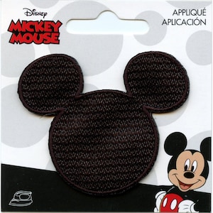 May include: Brown felt Mickey Mouse head iron-on patch. The patch is on a white card with black polka dots and the words "Disney Mickey Mouse" and "Applique Application".