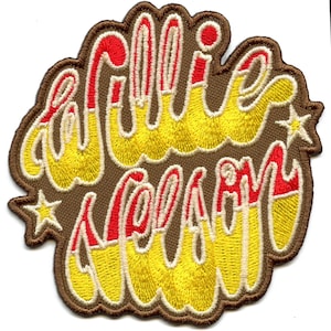 Puede incluir: Un parche bordado marrón con las palabras "Willie Wonka" en letras amarillas y rojas con una estrella a cada lado.