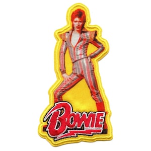 May include: A yellow embroidered patch featuring a red and white striped jumpsuit with a red lightning bolt and the word "BOWIE" in red and white lettering.