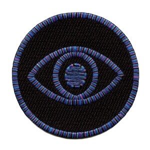 May include: A round, black embroidered patch with a colorful eye design. The eye is outlined in purple and blue, with a smaller circle in the center. The patch is perfect for adding a unique touch to clothing, bags, or other accessories.