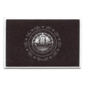 May include: A black embroidered patch with a white seal featuring a ship and a star. The seal is surrounded by a wreath of leaves.