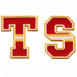 May include: Red and gold felt letters that spell out "TS". The letters have a white stripe across the middle.