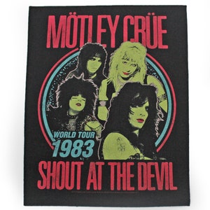 May include: Black and white band patch with a red and blue circle around a group of four people. The text "MÖTLEY CRÜE" is in red at the top, "WORLD TOUR 1983" is in blue and white in the centre, and "SHOUT AT THE DEVIL" is in red at the bottom.
