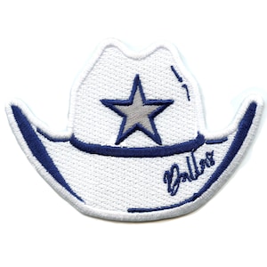 Puede incluir: Sombrero vaquero blanco con una estrella azul y la palabra "Dallas" bordada en el lateral.
