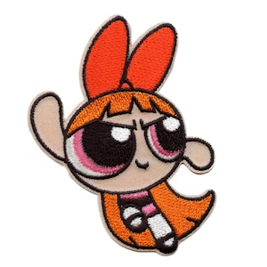 May include: Embroidered patch of Blossom from The Powerpuff Girls. The patch depicts Blossom with her orange hair, pink eyes, and a determined expression. The patch is outlined in black and beige, with a white background.