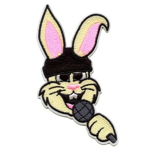May include: An embroidered patch of a cartoon rabbit wearing a black bandana and holding a microphone. The rabbit has pink ears and a yellow face.