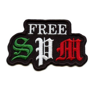 May include: A black embroidered patch with the words "FREE" in white and "SPM" in green, white, and red, resembling the Italian flag.