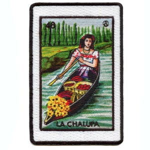 Puede incluir: Un parche bordado colorido que presenta a una mujer en un bote con frutas y flores. El texto "LA CHALUPA" está en la parte inferior del parche.
